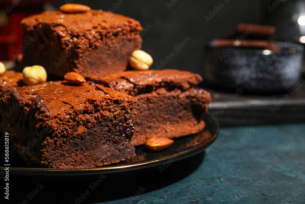 Plate with pieces of tasty chocolate brownie on black background, closeup