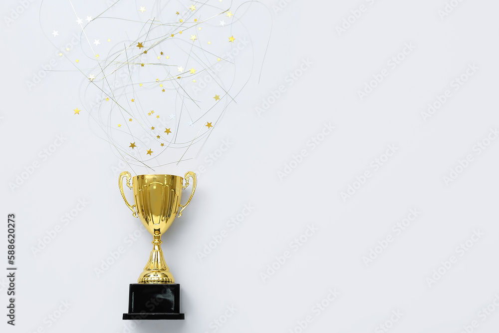 Gold cup with confetti on light background