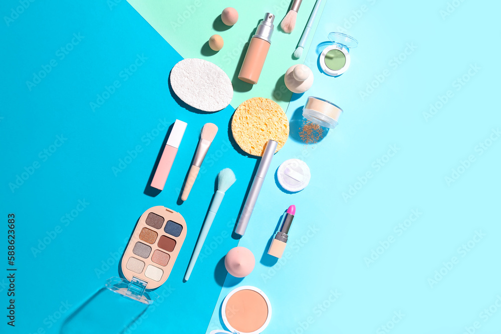 Decorative cosmetics with makeup brushes and sponges on color background