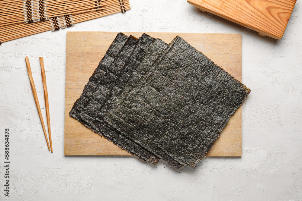 Wooden board with nori sheets on light background