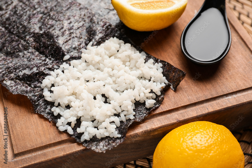 Wooden board of nori with rice on table, closeup