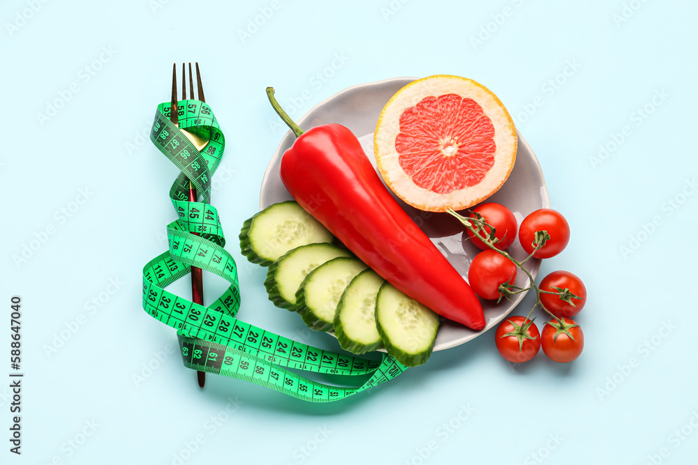 Composition with vegetables, grapefruit and green measuring tape on blue background. Diet concept