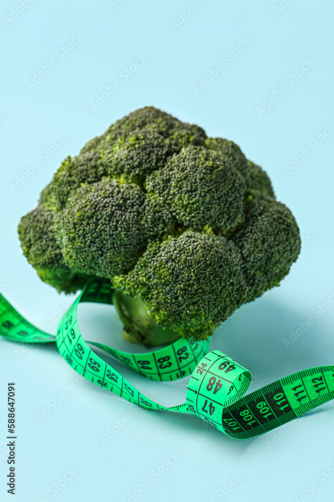 Broccoli and green measuring tape on blue background. Diet concept