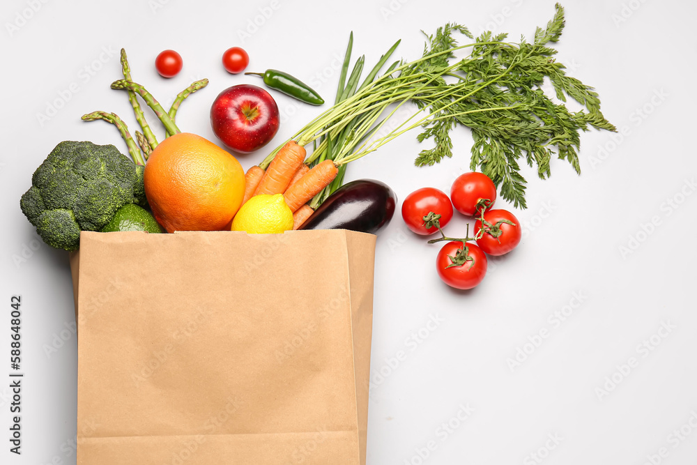 Paper bag with vegetables and fruits on grey background