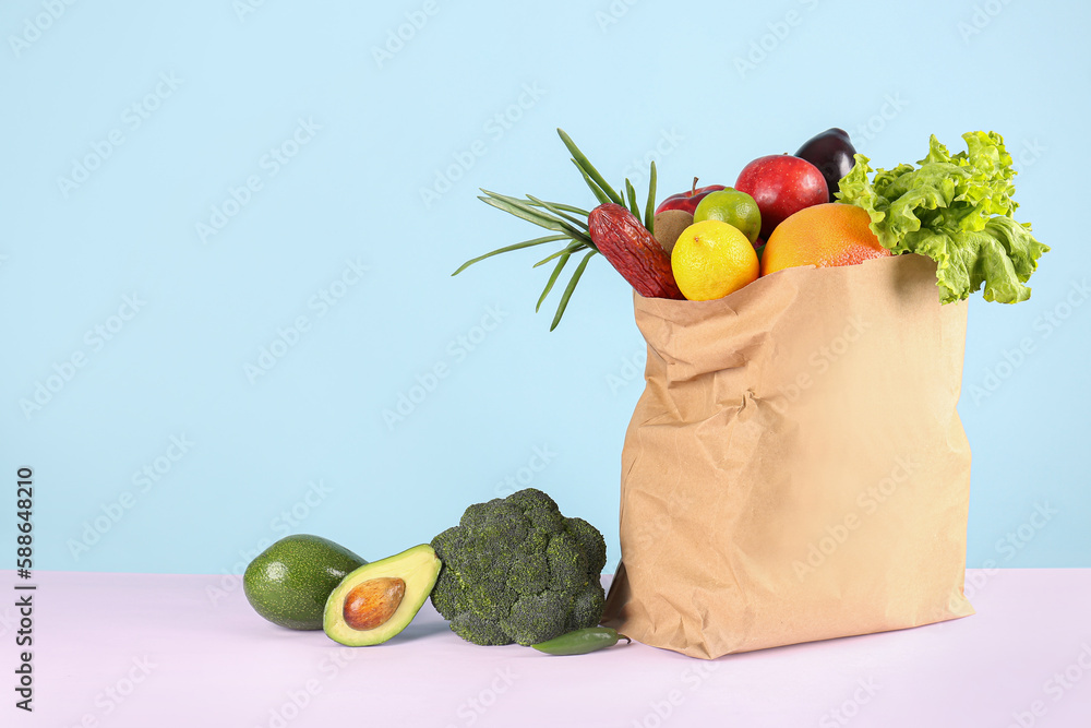 Paper bag with vegetables, fruits and sausage on table