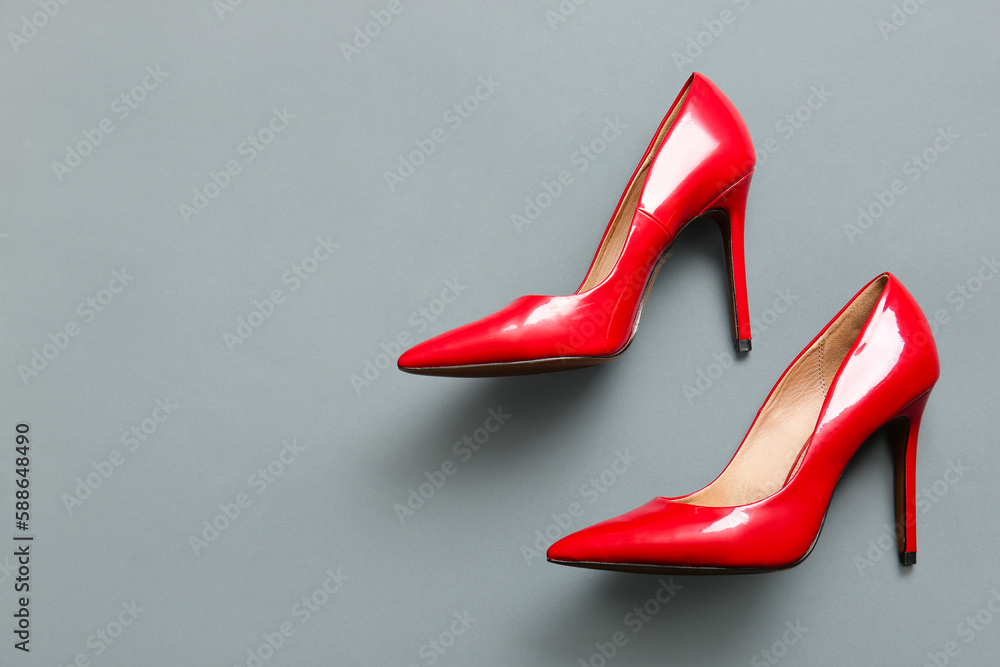 Pair of red high heeled shoes on grey background