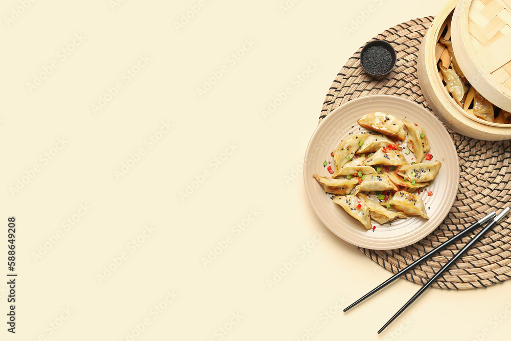 Plate with tasty Chinese jiaozi, sesame and bamboo steamer on beige background