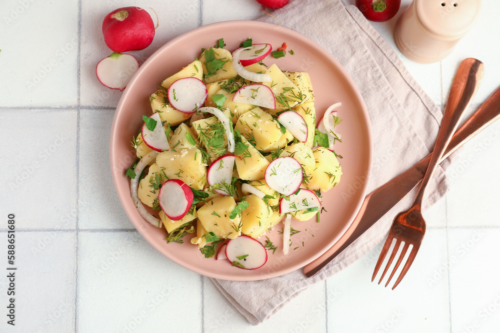 Plate of tasty Potato Salad with vegetables on white tile background