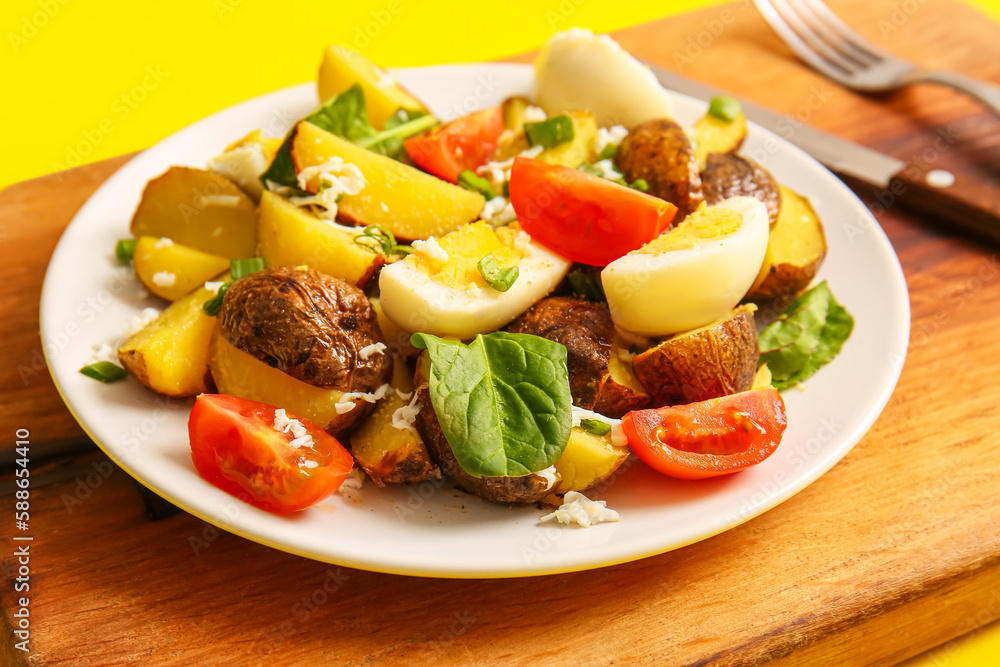 Plate of tasty potato salad with eggs and tomatoes on wooden board