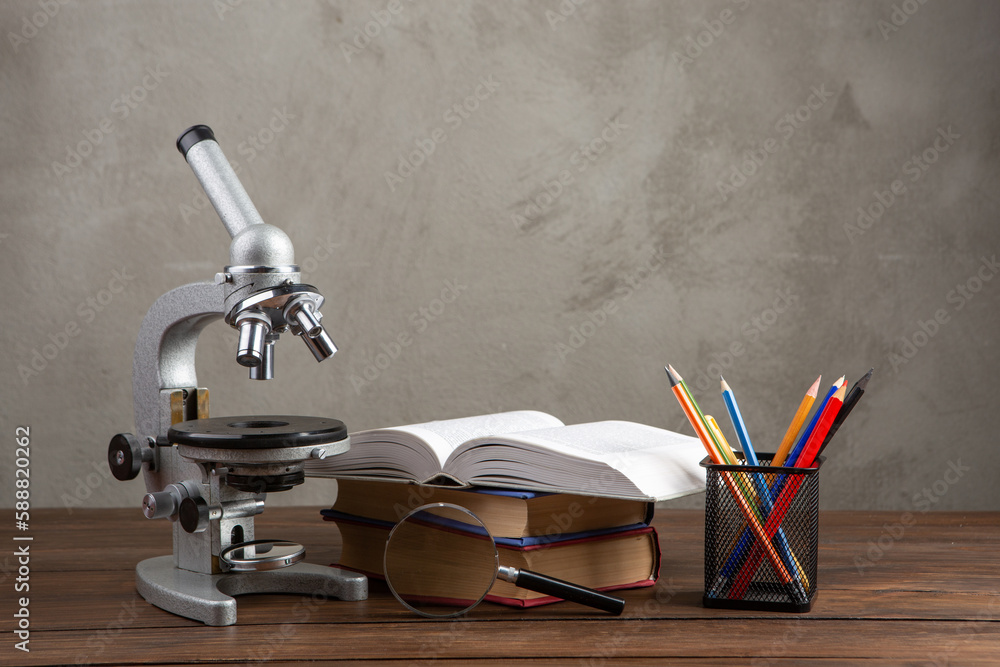 Back to school - books and microscope on the wooden desk in the auditorium, Education concept