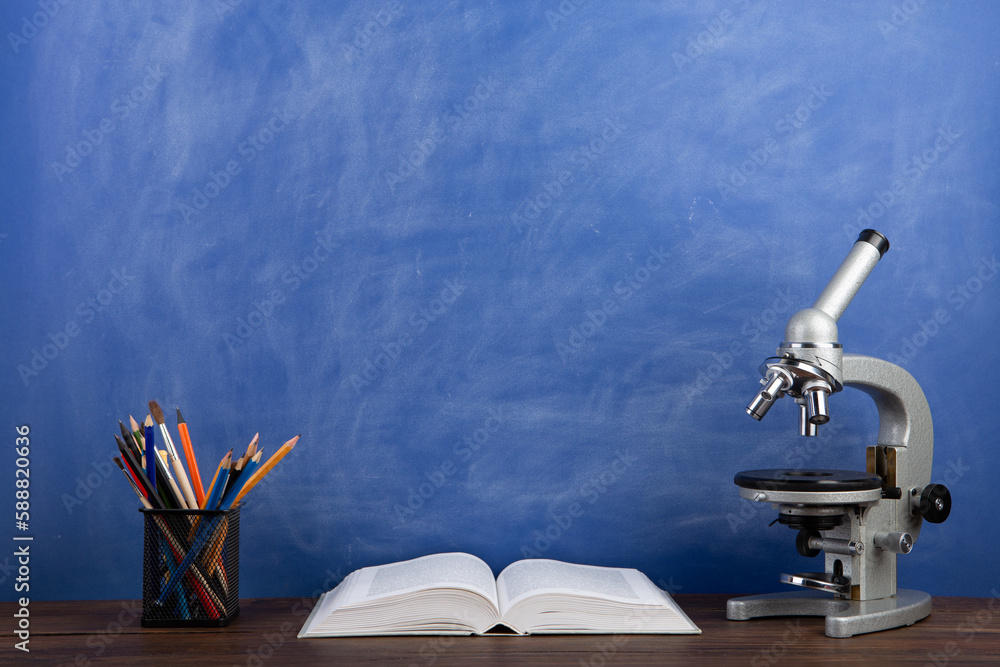 Back to school - books and microscope on the desk, Education concept. Blackboard background