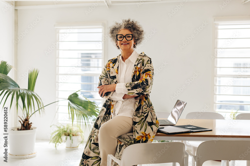 Happy businesswoman sitting on a table in a meeting room