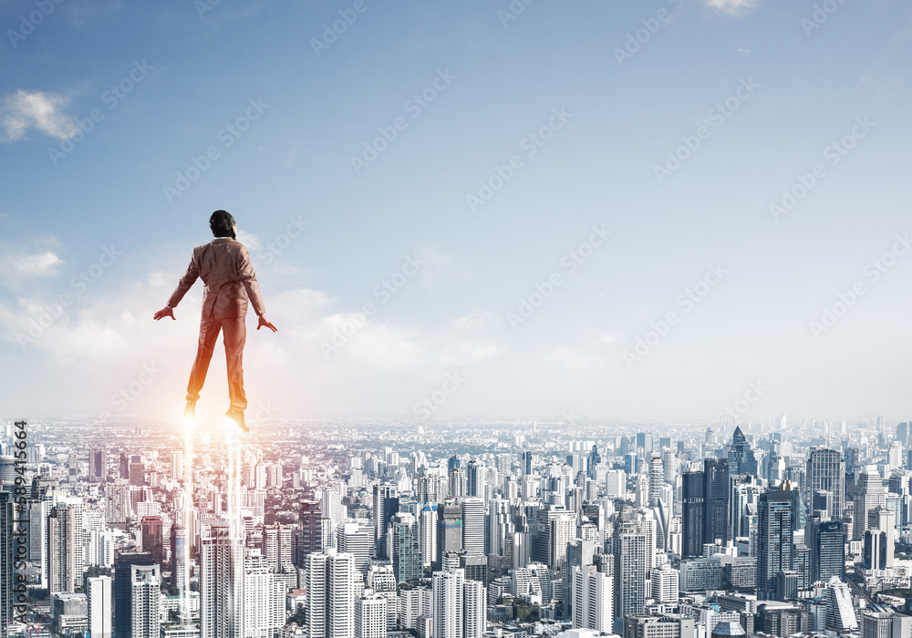 Businessman in suit and aviator hat flying in sky