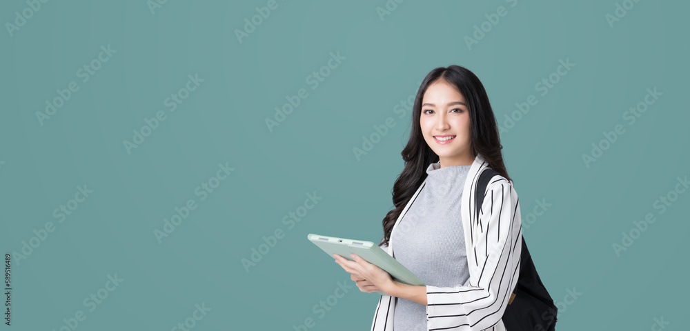 Young Asian girl college student with tablet and backpack isolated over teal background