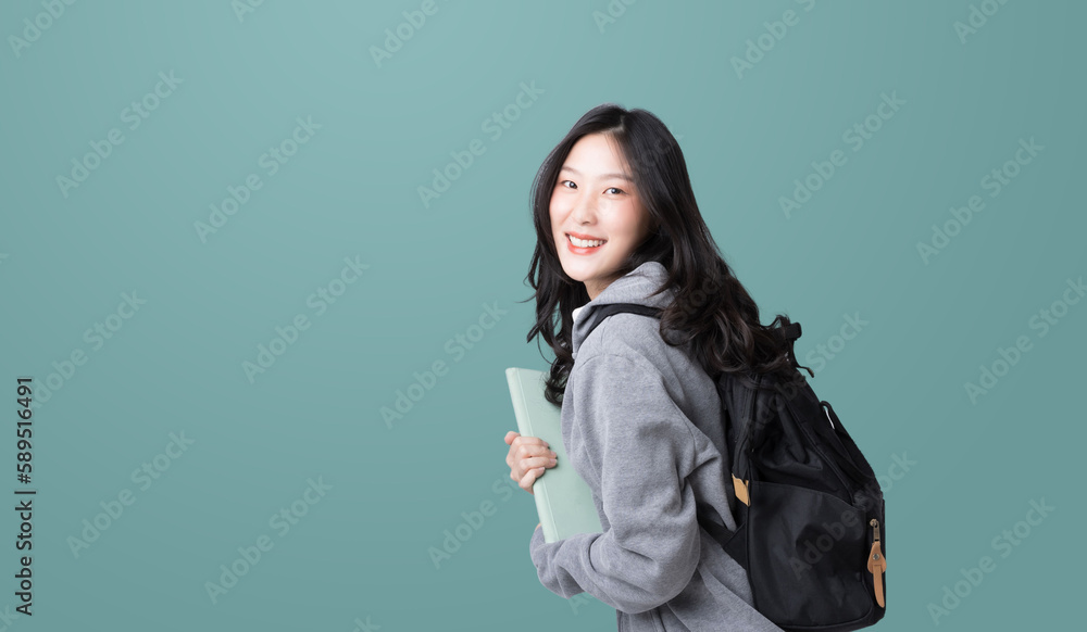 Young Asian girl college student with tablet and backpack isolated over teal background