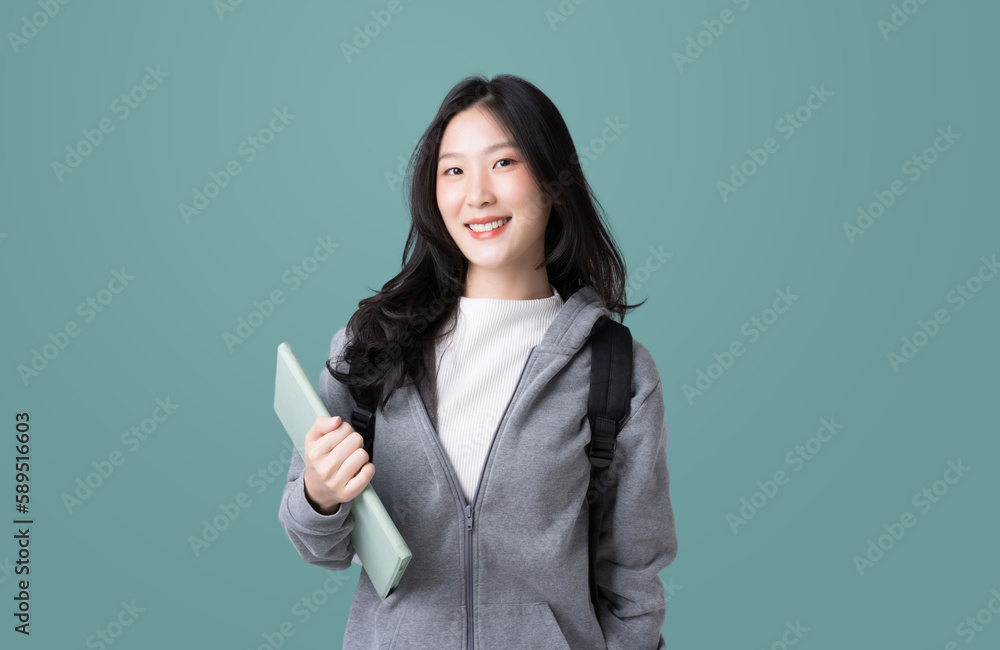 Young Asian girl college student with tablet and backpack isolated over teal background