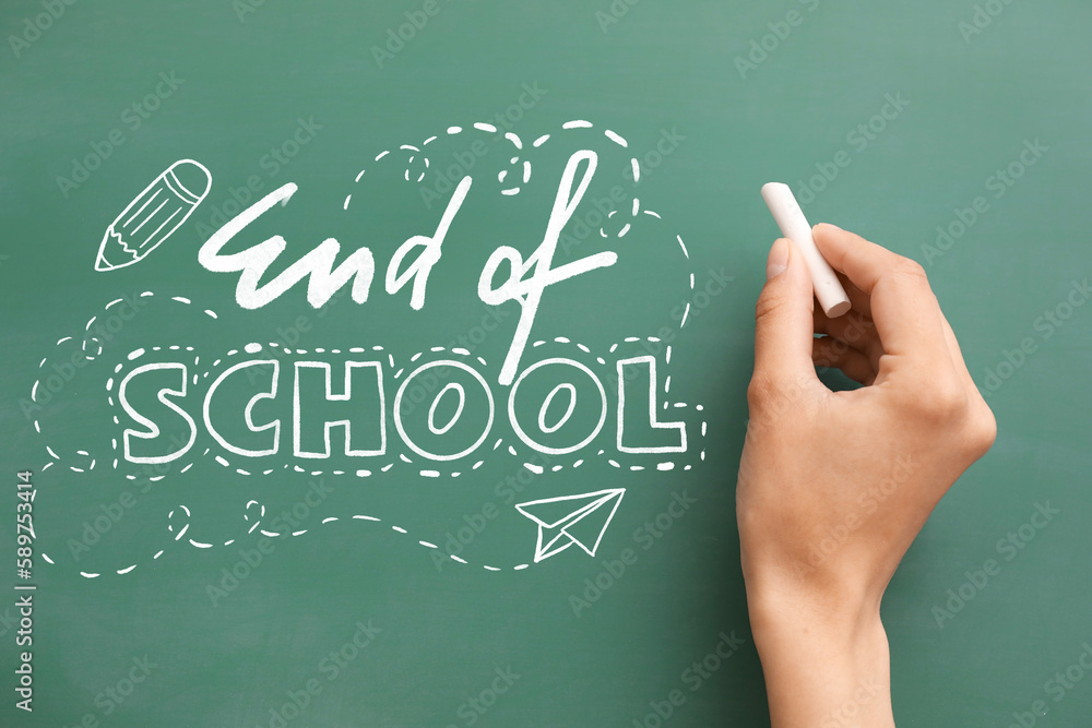 Hand writing text END OF SCHOOL on blackboard