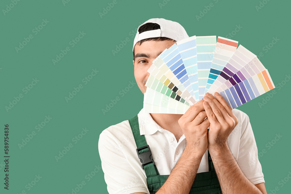 Male painter with color palettes on green background, closeup