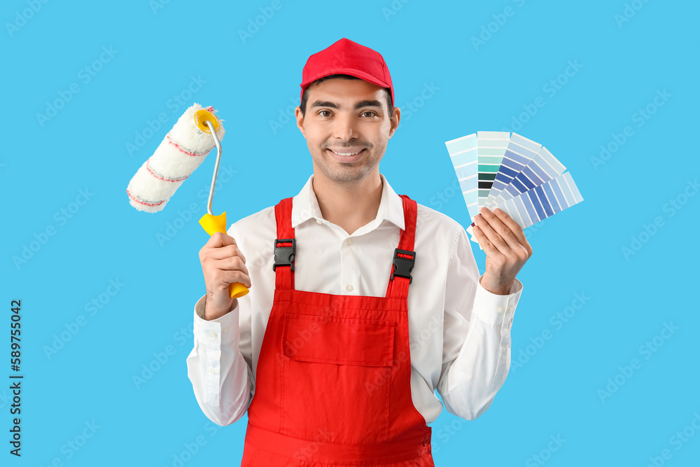 Male painter with color palettes and roller on blue background