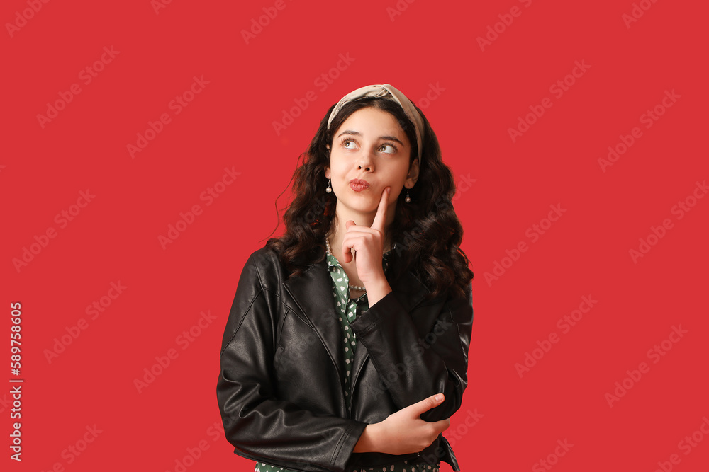 Thoughtful teenage girl in leather jacket on red background