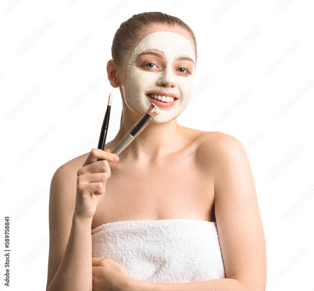 Young woman with applied turmeric mask and brushes on white background