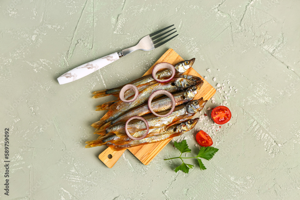 Board with tasty smoked capelin, onion rings and sea salt on grey background