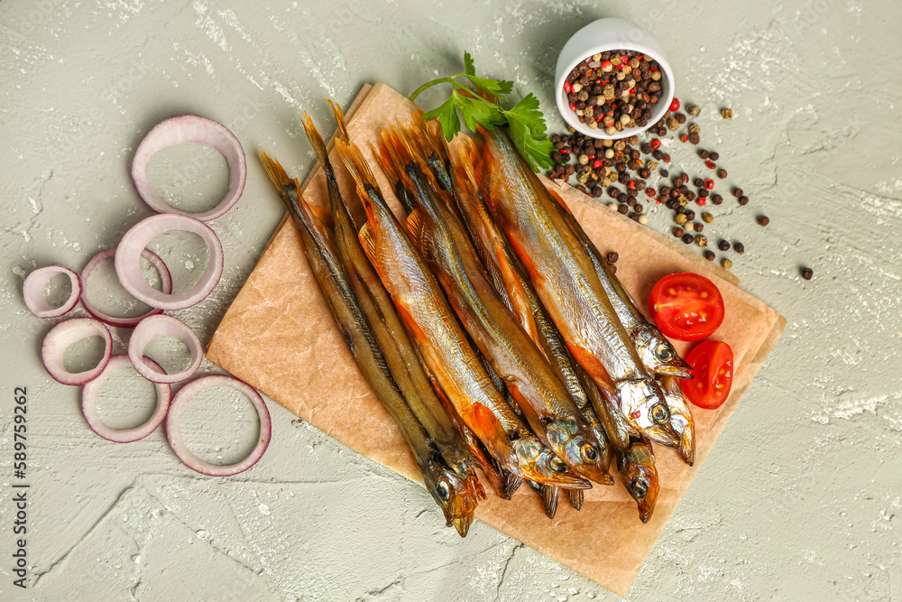 Parchment with tasty smoked capelin on grey background