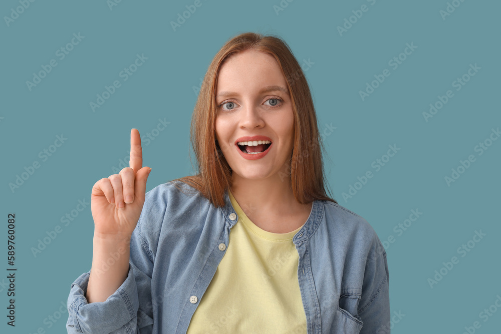 Beautiful redhead woman pointing at something on blue background