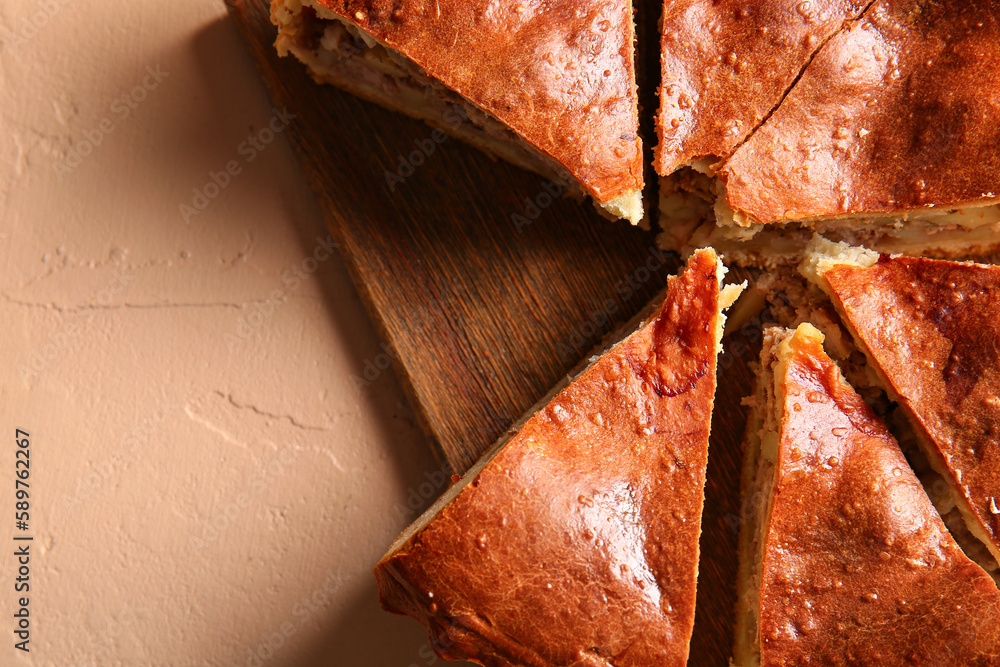 Board with pieces of delicious meat pie on beige table, closeup