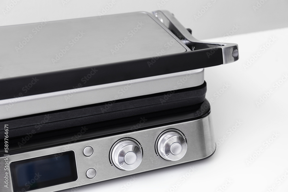 Modern electric grill with closed lid on white table, closeup