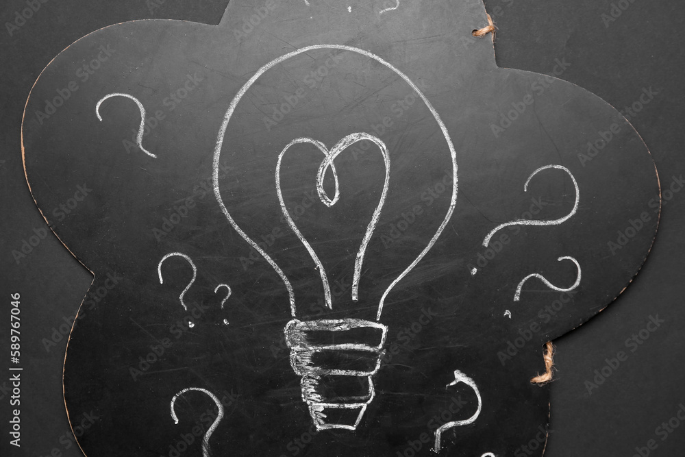 Chalkboard with drawn light bulb and question marks on black background. Insight concept