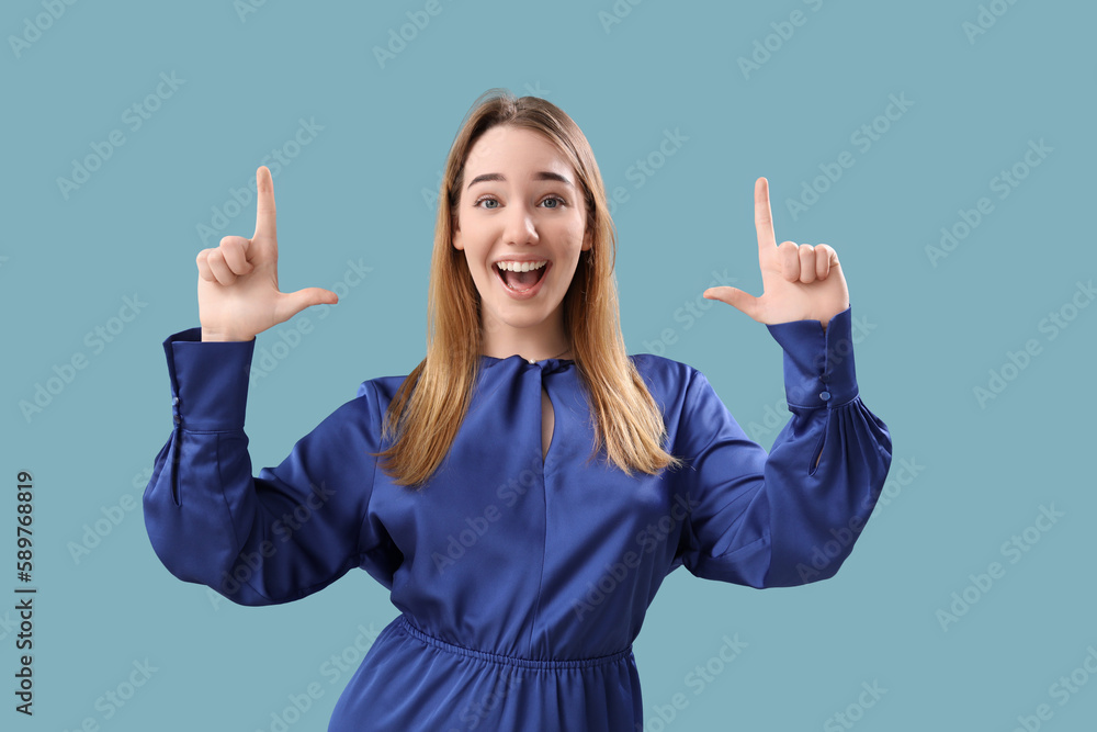 Young woman showing loser gesture on blue background