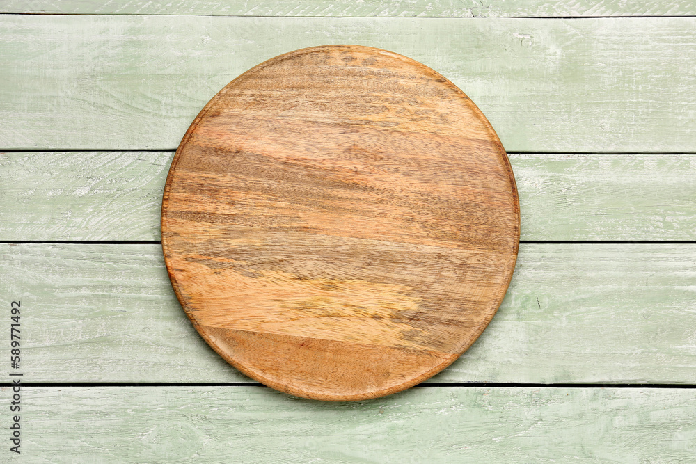 Round cutting board on color wooden background