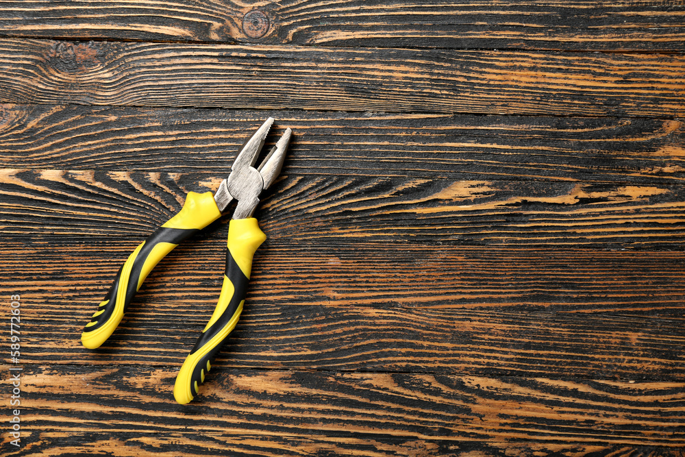 Yellow pliers on wooden background