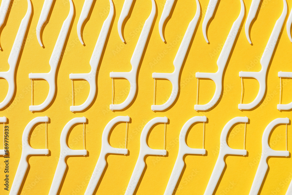 Many floss toothpicks on yellow background