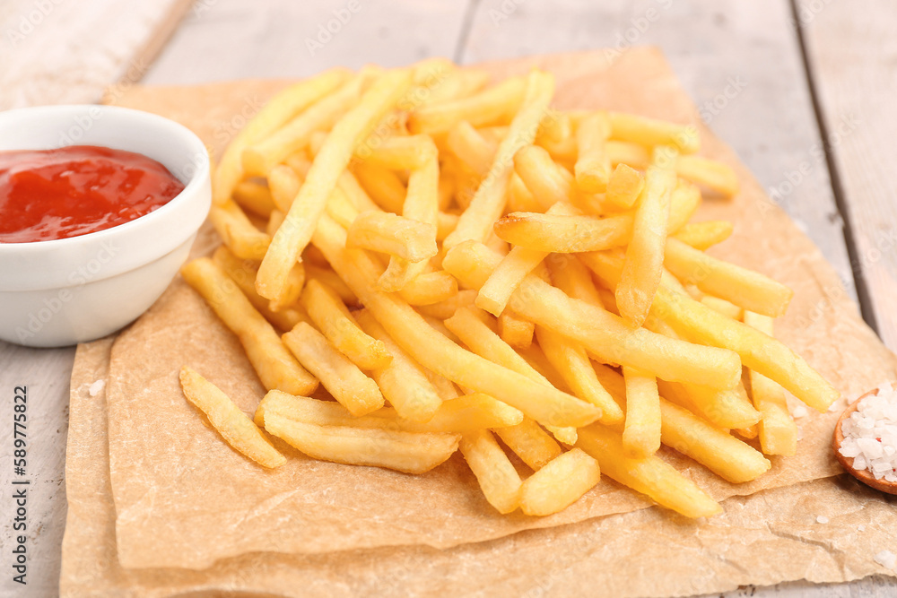 Tasty french fries, salt and ketchup on wooden background