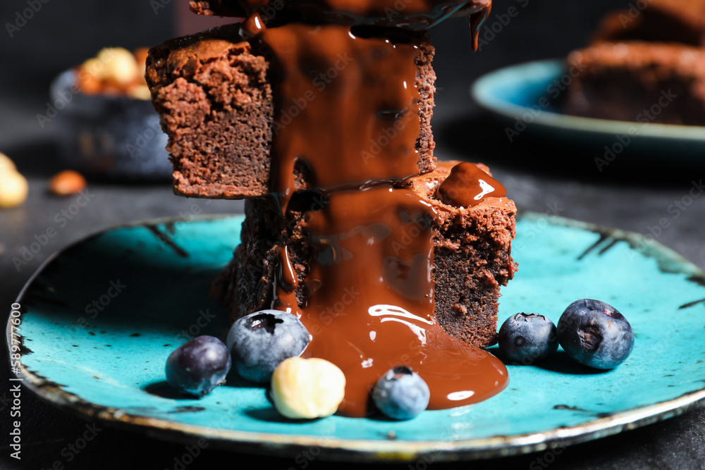 Plate with pieces of tasty chocolate brownie on black background