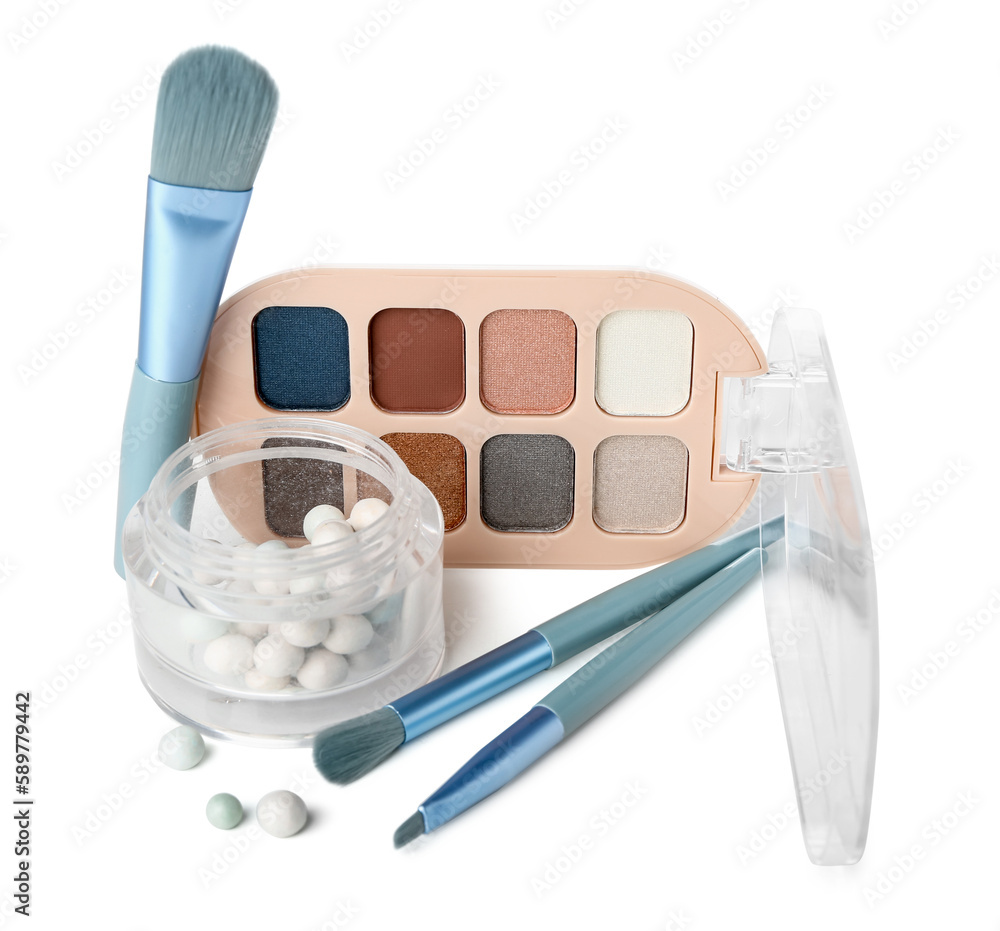 Makeup brushes with powder pearls and eyeshadows on white background