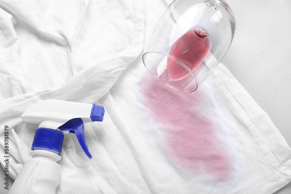 Laundry detergent with spilled wine and stained clothes on light background, closeup