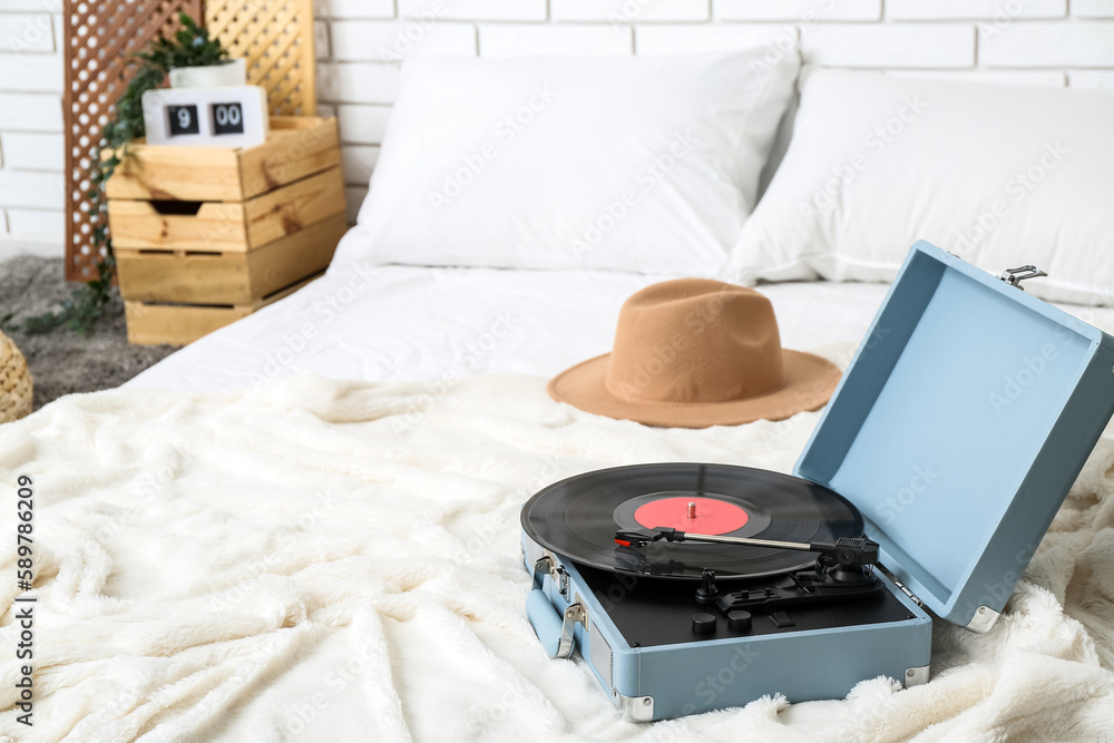 Record player with vinyl disk on bed in room