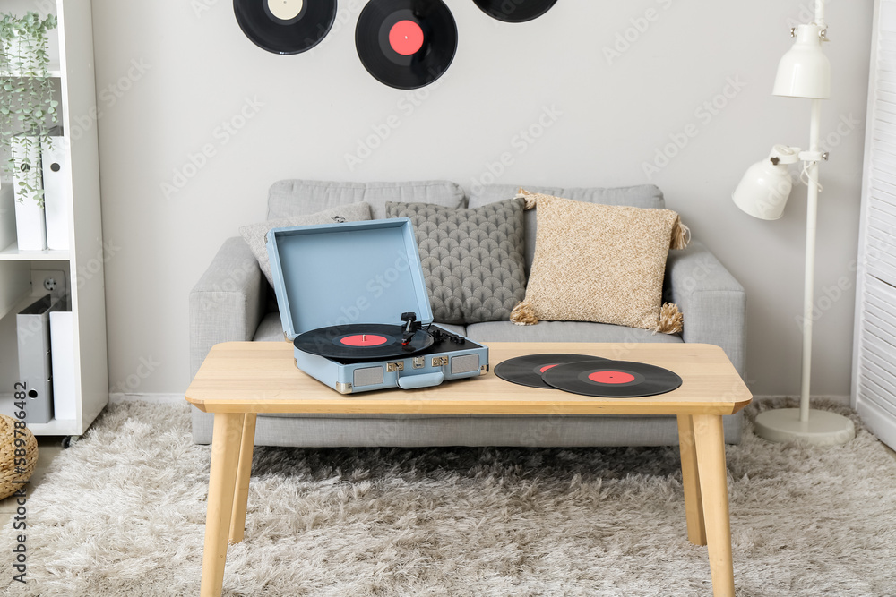 Record player with vinyl disks on table in interior of living room