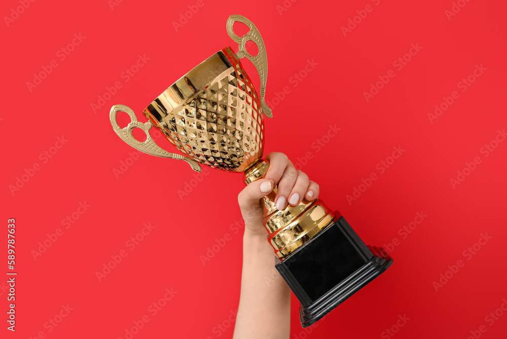 Woman with gold cup on red background