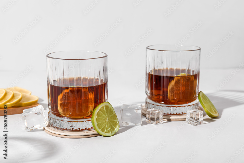 Glasses of cold rum with lime on grey background