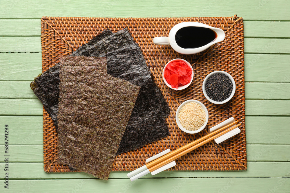 Nori sheets with sauce, sesame seeds and ginger on green wooden background