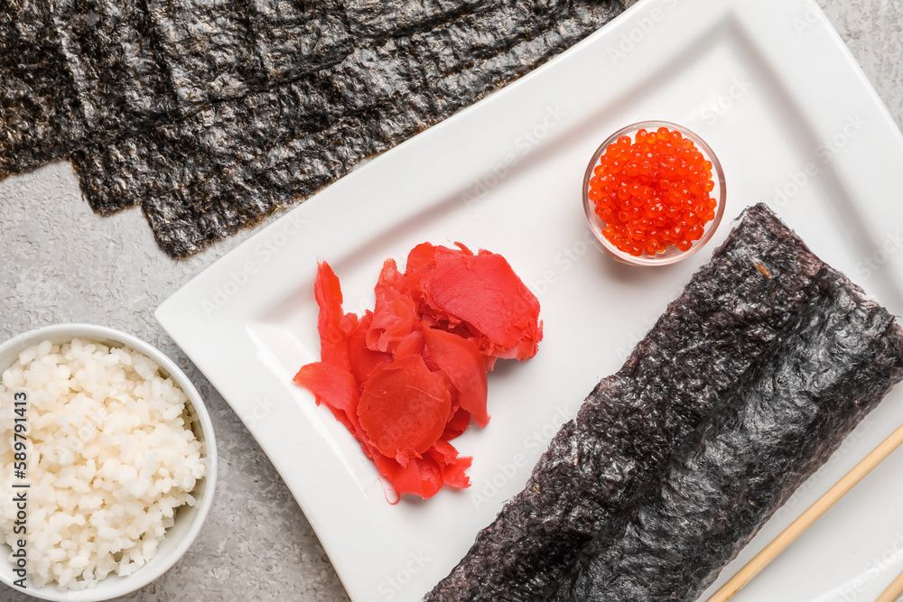 Plate of tasty sushi roll with ingredients on light background, closeup