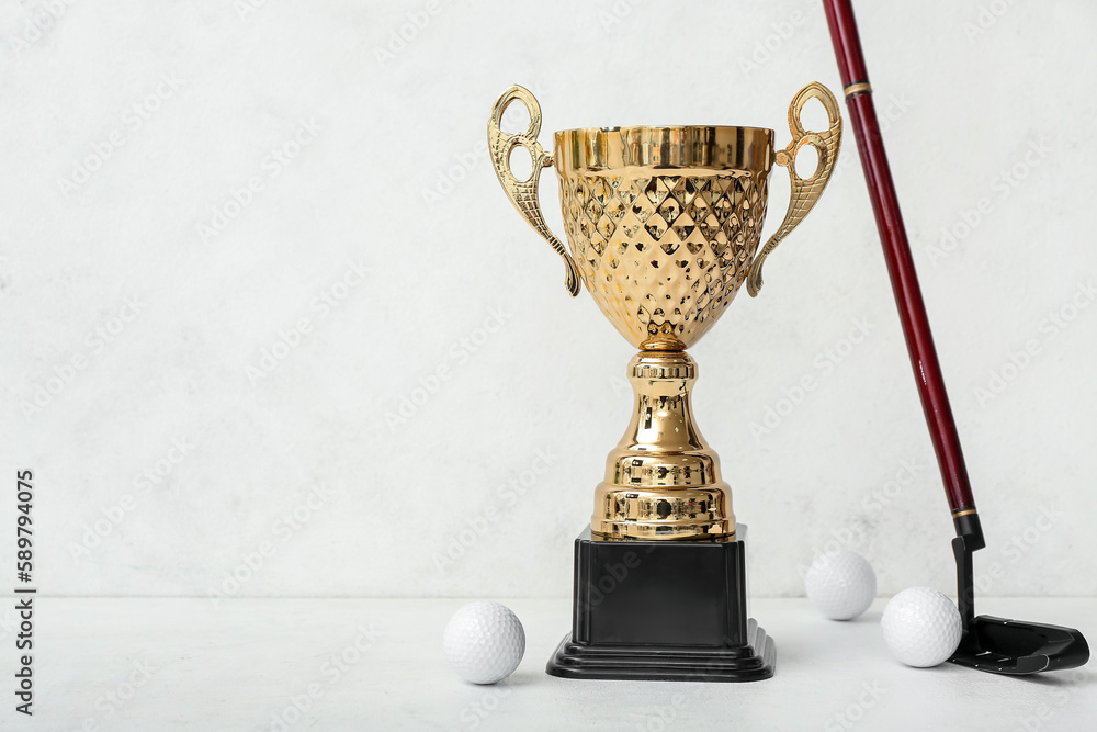 Gold cup with golf club and balls on light background