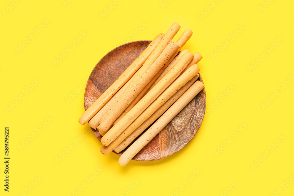 Plate with tasty Italian Grissini on yellow background