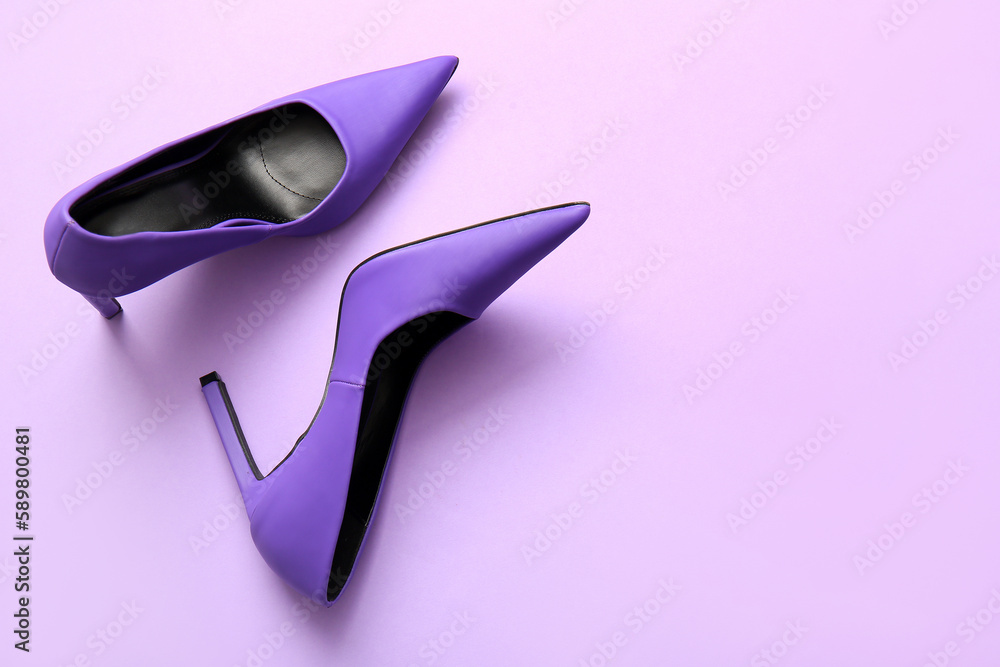 Pair of stylish high heeled shoes on lilac background