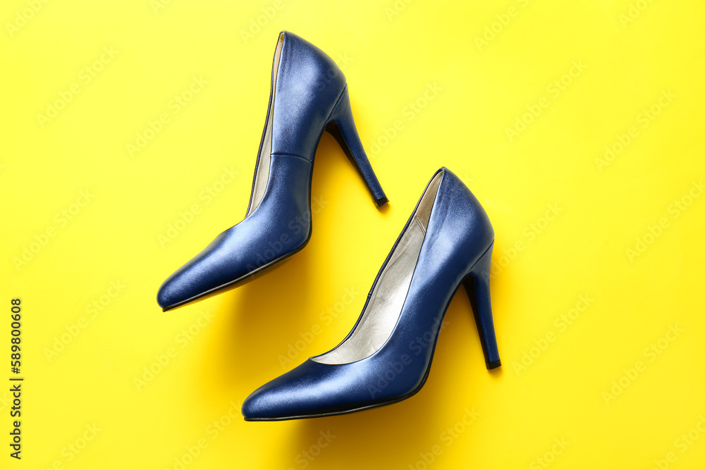 Pair of stylish high heeled shoes on yellow background