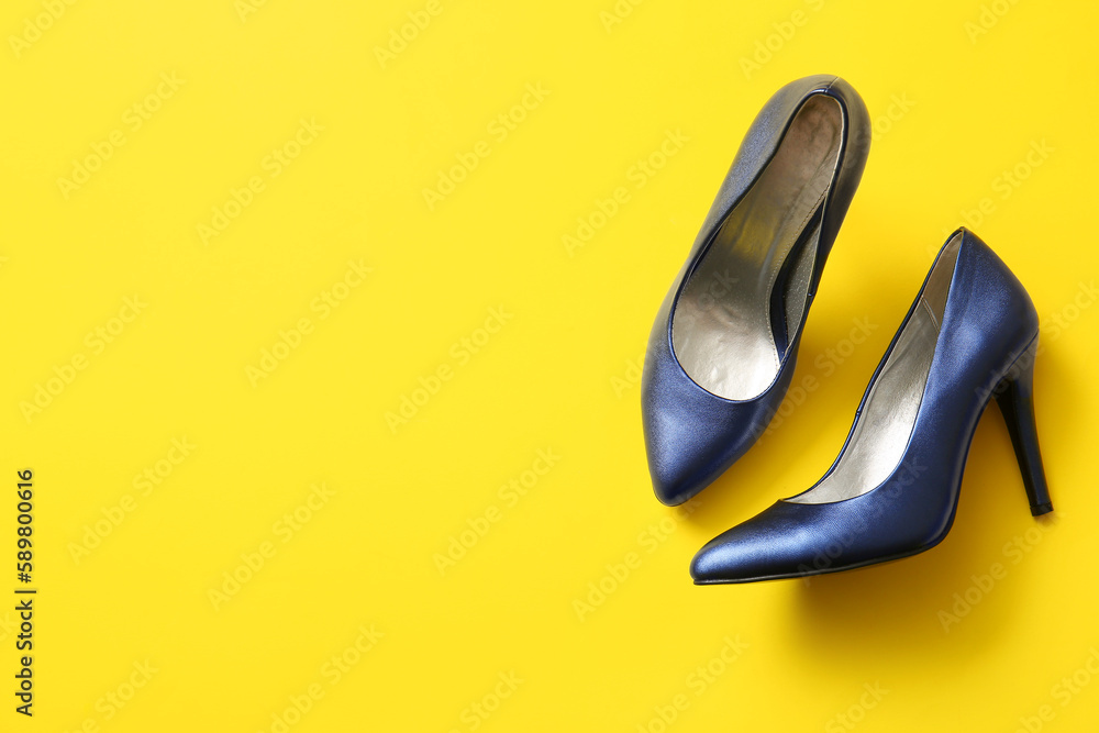 Pair of stylish high heeled shoes on yellow background